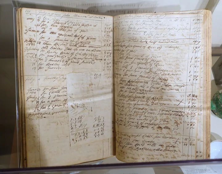 Photo d’origine : Livre de comptes ancien ouvert, aux colonnes tracées à la main et aux écritures manuscrites.