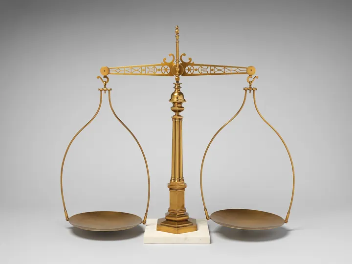 Original photo: Une balance à plateaux en laiton sur un socle de marbre, plateaux vides en équilibre.