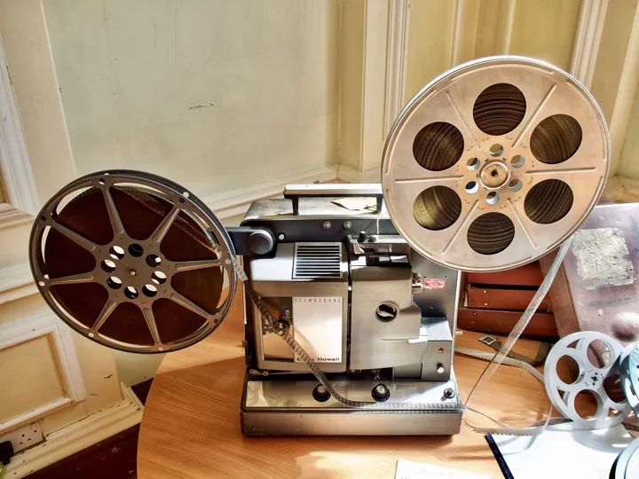Photo d’origine : Un vieux projecteur de cinéma à bobines posé sur une table.