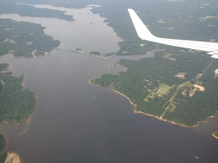 Original photo: Vue aérienne d’un grand lac aux rives boisées, traversé par une chaussée.