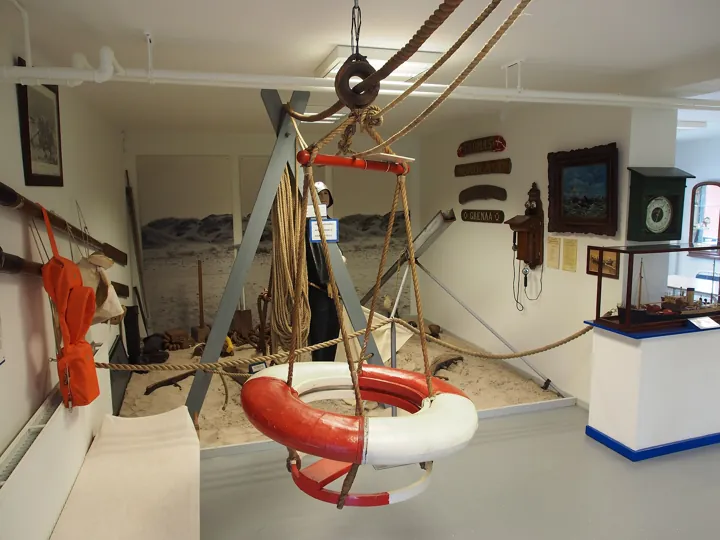 Photo d’origine : Bouée de sauvetage suspendue à un portique de corde dans un musée de sauvetage en mer : le secours prêt à servir