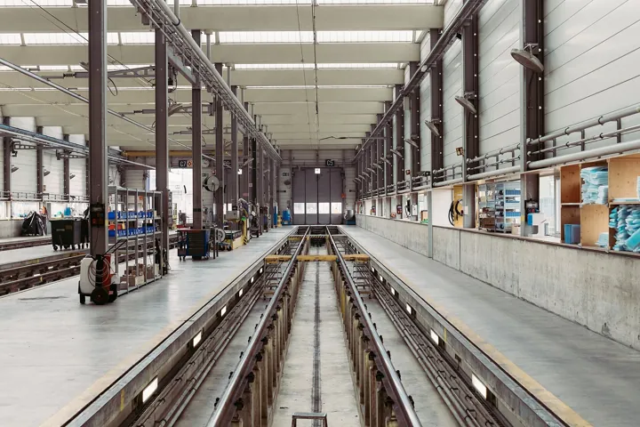 Original photo: Nef d’un atelier d’entretien ferroviaire, avec sa fosse et ses rails, ses étagères et ses rangements alignés.