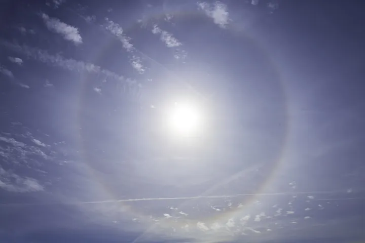 Original photo: Un halo lumineux en anneau autour du soleil dans un ciel bleu.