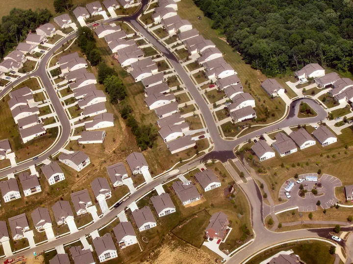 Photo d’origine : Vue aérienne d'un lotissement de maisons presque identiques le long de rues sinueuses.