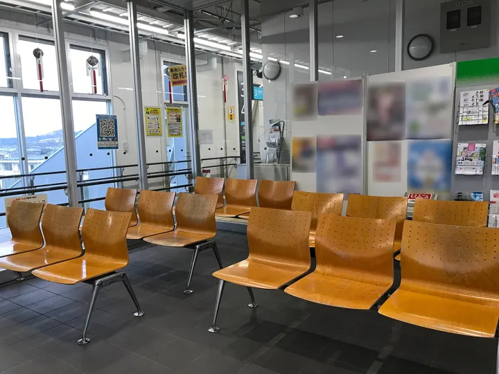 Original photo: Des rangées de sièges de bois vides dans une salle d'attente de gare.